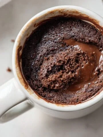 Freshly made Nutella mug cake in a white mug on a kitchen counter, top-down view.