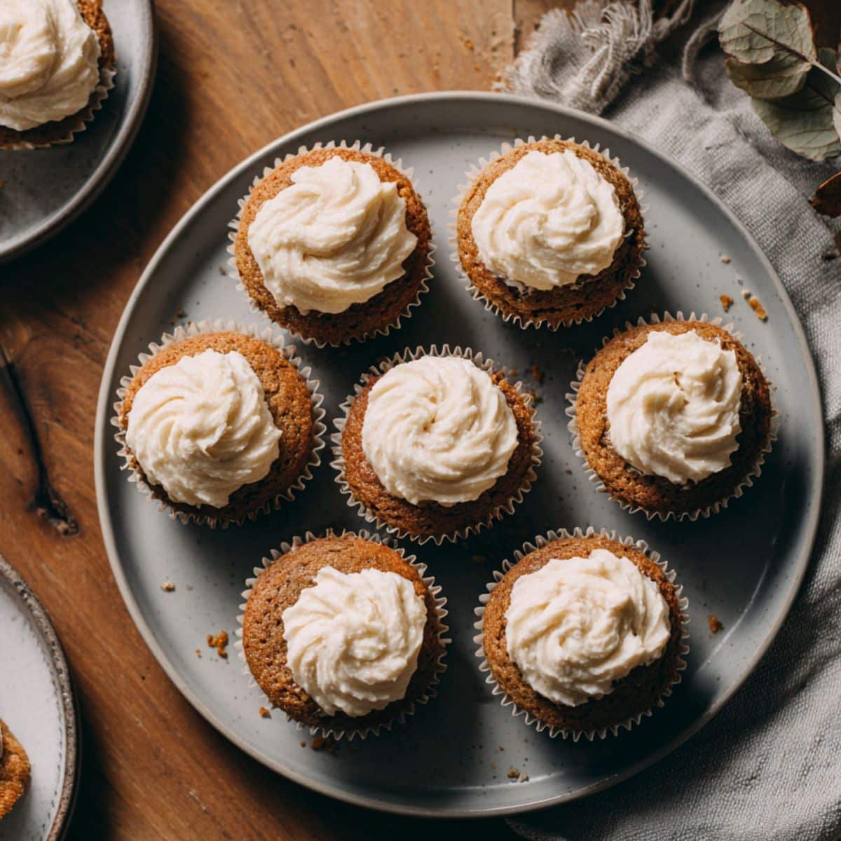Homemade pumpkin ginger cupcakes with cream cheese frosting on a white table, photographed from above.