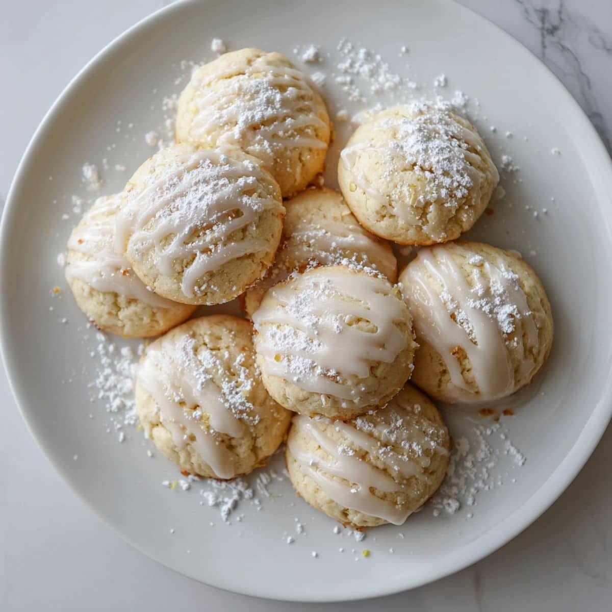 Homemade Italian ricotta cookies recipes cooling on a wire rack with a light lemon glaze on a white kitchen table.