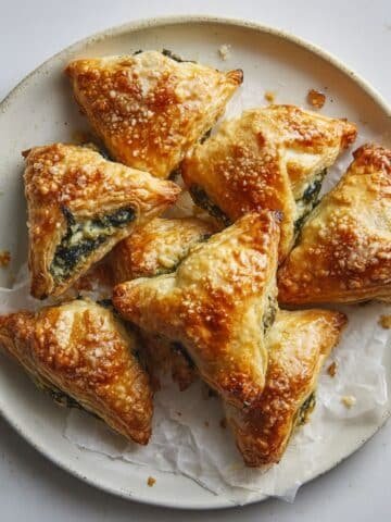 Golden homemade spinach puff pastries cooling on a white kitchen counter, captured from above with a warm natural light.
