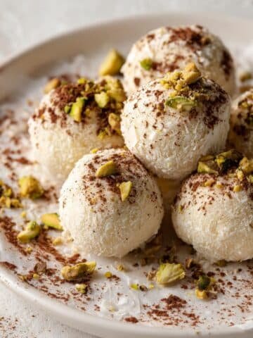 Homemade white chocolate truffles on parchment paper, photographed from above on a white kitchen table with natural light.