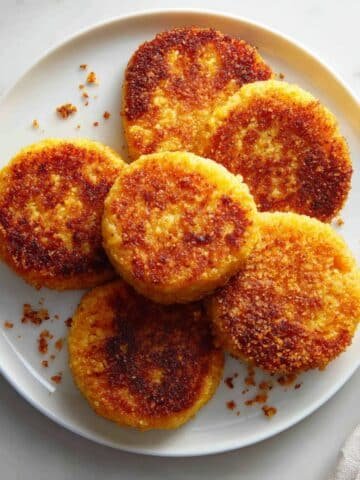 Crispy golden hot water cornbread patties on a white kitchen table, shot from above in natural light.