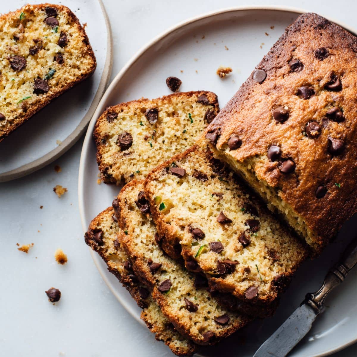 Homemade keto zucchini bread loaf on white table.