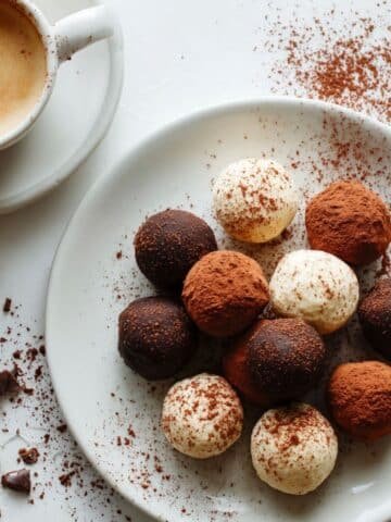 Homemade tiramisu truffles dusted with cocoa on a white kitchen table.