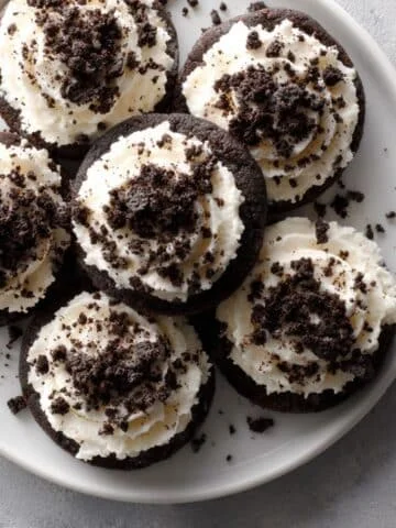Homemade Oreo Crumbl cookie topped with cream cheese frosting and crushed Oreos on a white kitchen counter.