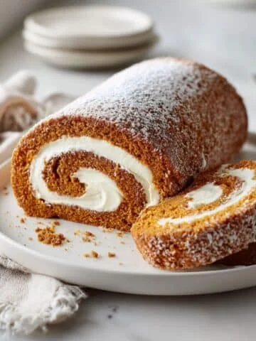 slice of pumpkin spice roll cake with cream cheese filling on white plate