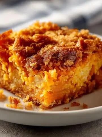 Homemade sweet potato dump cake with golden crust on a white kitchen table.