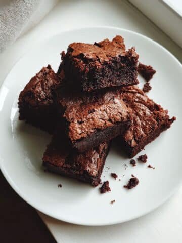 Fudgy homemade keto brownies recipe cooling on a white kitchen counter, shot from above.