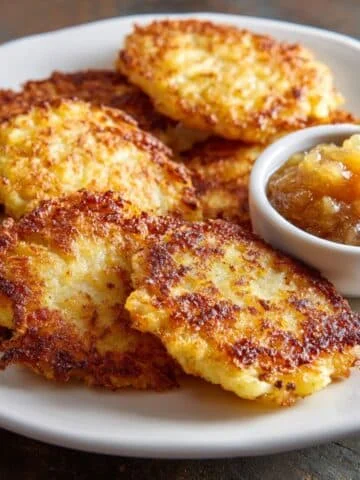 Homemade German potato pancakes served with applesauce on a white kitchen table, shot from above in natural light.